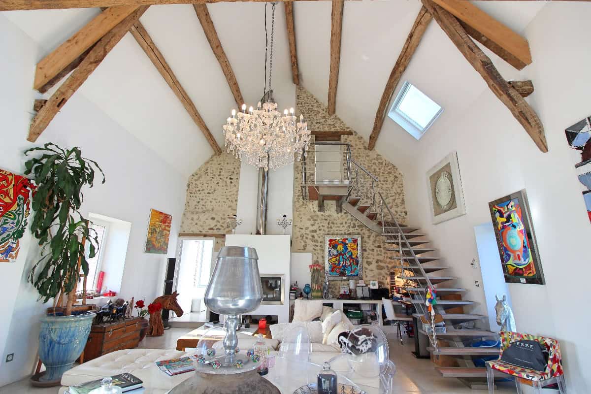 Séjour de maison de caractère avec poutres apparentes et murs en pierre